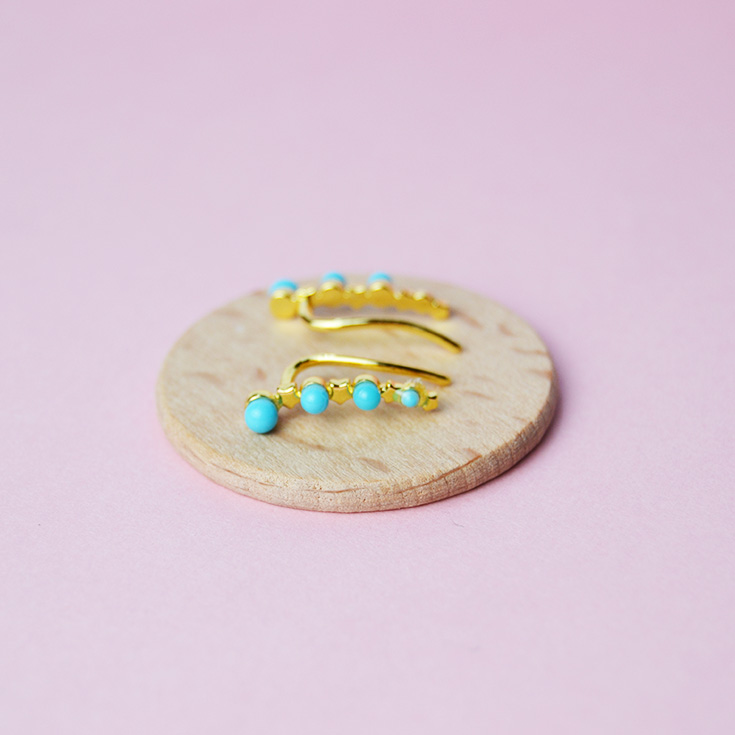 par de pendientes trepadores dorados con perlas azules